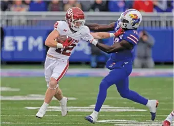  ?? AP PHOTO/CHARLIE RIEDEL ?? Oklahoma receiver Drake Stoops tries to get away from Kansas linebacker Craig Young during the first half of a Big 12 matchup Saturday in Lawrence, Kan.