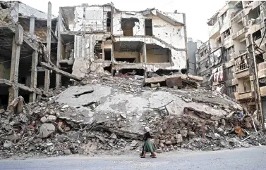  ??  ?? Syrian girls walk past destroyed buildings in the opposition-held town of Douma on the eastern outskirts of Damascus, Saturday. Fighting subsided in Syria after a deal to create four safe zones began to take effect. (AFP)
