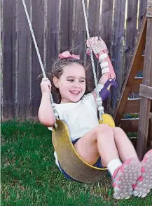  ?? Family photo ?? The prothestic hand created for Katelyn Vincik with the use of a 3-D printer “makes everything in the world easier,” including playing on the family’s swingset in their backyard in Victoria.