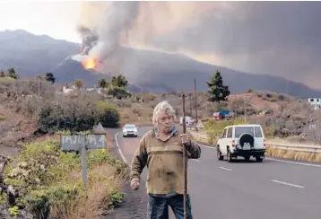  ?? EMILIO MORENATTI/AP ?? A resident takes a walk around his house Wednesday, near the erupting volcano, on the Canary island of La Palma, Spain. Officials say a volcano erupting for the past five weeks on the Spanish island is more active than ever. New lava flows have emerged following a partial collapse of the crater and threaten to engulf previously unaffected areas.