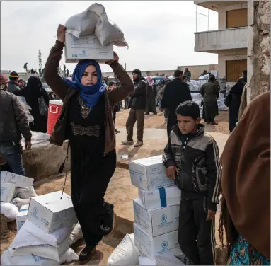  ??  ?? A displaced Syrian woman carries a box of humanitari­an aid in Idlib, Syria. Turkey’s President Recep Tayyip Erdogan said he would order imminent operations in Idlib if Damascus fails to withdraw behind Turkish positions in the stand-off there