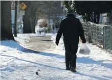  ?? — THE CANADIAN PRESS FILES ?? A man navigates an ice-covered street in Vancouver. Some residents seem reluctant to clear their sidewalks.