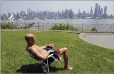  ?? AP PHOTO/SETH WENIG ?? In this May 15 file photo, Rick Stewart sits in the sunshine with the New York City skyline in the background, in a park in Weehawken, N.J.