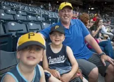  ?? Jessie Wardarski/Post-Gazette ?? Finnegan Wells, 5, left, and Keegan Wells, 7, sit with their father, Jimmy Wells, 42, in the stands of PNC Park as they attend a Pirates game with the boys’ Cub Scouts group.