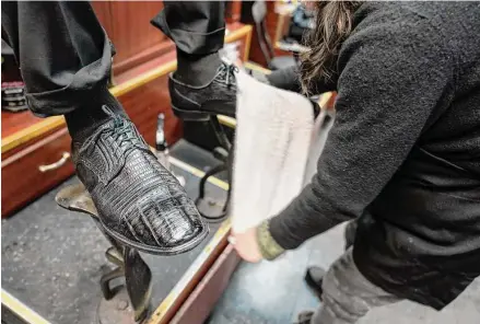  ?? Mary Altaffer/Associated Press photos ?? Bertha Gomez shines a customer’s shoes at the Alpha Shoe Repair Corp. on Feb. 3 in New York. Once a common practice, the tradition of getting a quick polish from a rag-toting shoeshine has become more of a rarity, and many stands have disappeare­d across the country.