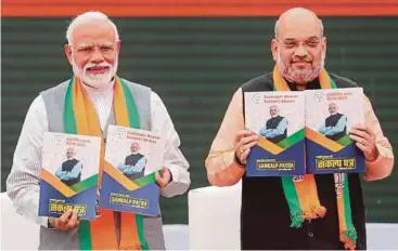  ?? REUTERS PIC ?? Indian Prime Minister Narendra Modi (left) and Bharatiya Janata Party chief Amit
Shah showing copies of their party’s election manifesto in New Delhi yesterday.