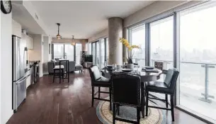  ?? XINGYI WANG PHOTOS HOUSSMAX ?? The 1,048-square-foot condo has an open layout with hardwood flooring and walls of windows that provide views of both Lake Ontario and the city.