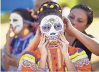  ??  ?? Natalie Valdez is gets help from Shalena Baldenegro before performing with Ballet Folklorico Quetzalli at the sixth annual Día de Los Muertos PHX Festival on Sunday.