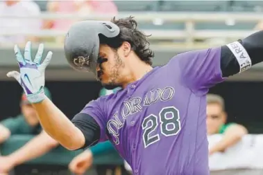  ??  ?? Nolan Arenado’s batting helmet comes off Thursday after a swinging strike during the Rockies’ Cactus League game against the Athletics in Mesa, Ariz. Arenado says of teammate Carlos Gonzalez, who had a rough season last year: “CarGo has a lot left, and...