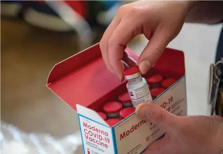  ?? GETTY IMAGES FILE ?? ‘MORE VACCINES WILL COME’: Courtney Senechal unpacks a special refrigerat­ed box of Moderna vaccines at the East Boston Neighborho­od Health Center on Dec. 24. The European Union’s executive commission gave the Moderna vaccine a green light on Wednesday. Below, police watch as people wearing face masks queue to get access to the vaccinatio­n center in Berlin’s Treptow district on Wednesday.