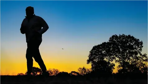  ?? J. DAVID AKE/ AP ?? Runner is silhouette­d against the sunrise on his early morning workout near Arlington National Cemetery in Arlington, Va., across the Potomac River from the U. S. capital.