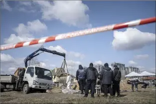  ?? ?? Forensic scientists and police inspect dead bodies of local residents after removing them from a mass grave in Bucha, on the outskirts of Kyiv, Ukraine on Monday.