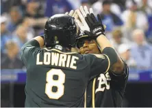  ?? Nathan Denette / Associated Press ?? Khris Davis celebrates with Jed Lowrie after hitting a two-run homer against the Blue Jays in the fifth inning.