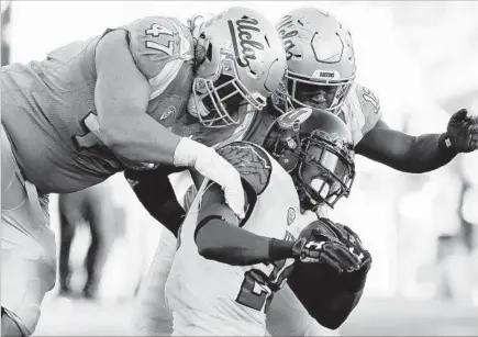  ?? Luis Sinco Los Angeles Times ?? THE UCLA DEFENSE rarely got a handle on Utah running back Joe Williams, though Eddie Vanderdoes, left, and Jayon Brown managed to bring him down in the fourth quarter. Williams rushed for 332 yards, a UCLA opponents’ record, and four touchdowns.