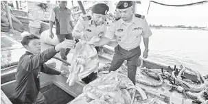  ?? — Gambar Bernama ?? RAMPASAN: Rahim (dua kanan) bersama anggota memeriksa hasil laut yang dirampas selepas bot nelayan Vietnam itu menceroboh perairan negara ini pada sidang media di Ibu Pejabat Maritim negeri dekat Kuala Terengganu, semalam.