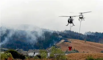  ?? PHOTOS: MARTIN DE RUYTER/STUFF ?? Helicopter­s with monsoon buckets fight the out of control Tasman fire near the Eves Valley Saw Mill.