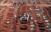  ?? ANDRE PENNER / AP FILE ?? In this April 7 file photo, cemetery workers wearing protective gear lower the coffin of a person who died from complicati­ons related to COVID-19 into a gravesite at the Vila Formosa cemetery in Sao Paulo, Brazil.