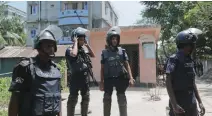  ??  ?? GOOD SHOW: Bangladesh policemen stand in front of a twostory house, (behind in blue), that they raided and killed the three militants in Narayangan­j district near Dhaka on Saturday. (AP)