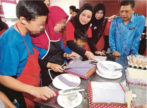  ?? [ FOTO NIK HARIFF HASSAN /BH ] ?? Anggraini Sentiyaki (tiga dari kanan) bersama Pengetua SBJK, Zulkernai Fauzi (kanan) bermesra dengan pelajar yang sedang membuat kek di kelas memasak di SBJK di Kuala Lumpur, baru-baru ini.