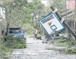  ?? AARON FAVILA — THE ASSOCIATED PRESS ?? A resident walks beside a toppled basketball hoop after Typhoon Mangkhut barreled across Tuguegarao city, Cagayan province, in the Philippine­s on Saturday.