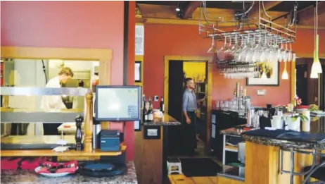  ?? Photos by Brent Lewis, The Denver Post ?? Evan Hartnett works in the kitchen while Travis Halbright peeks out to check on customers at Sugarbeet.