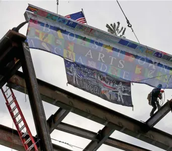  ?? MATT sTonE pHoTos / HERALD sTAFF ?? IT’S TOPS: The last steel beam is hoisted into position Tuesday during a topping-off ceremony for the $125 million Boston Arts Academy in the Fenway. At left, City Council President Kim Janey joins others in signing the beam before its trip skyward.