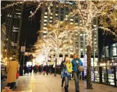  ?? MANNY RAMOS/SUN-TIMES; SUN-TIMES FILE PHOTO ?? Jahmal Cole (above, from left) and Casey Merchant recruited homeowners on Martin Luther King Drive to sign up for holiday lights. They want it to resemble the holiday lighting found downtown (left) and elsewhere.