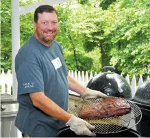  ??  ?? Randy Hill shows off a brisket cooked on one of his many grills at his home.