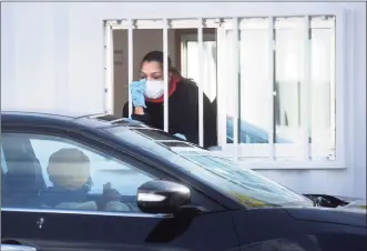  ??  ?? A medical technician gives directions for a self-administer­ed COVID-19 test kit to waiting patient at the Connecticu­t Department of Public Health’s new drive-thru testing site at Seaside Park in Bridgeport on Tuesday.