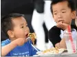  ?? PHOTO BY MILKA SOKO ?? Leon Gao, 3, enjoys his meal as his brother Galen, 5, looks at him during Eastvale’s first internatio­nal food festival on Saturday.