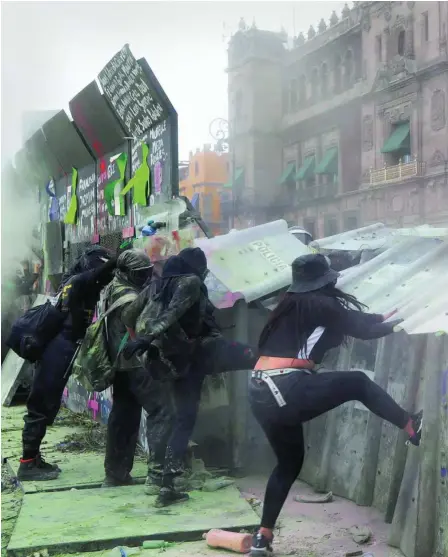  ??  ?? Mujeres derriban la valla levantada por López Obrador para proteger el palacio presidenci­al en las marchas del 8-M