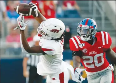  ?? Associated Press ?? Keep your eye on the ball: Arkansas wide receiver Trey Knox (7) tries to catch a pass as he is pressured by Mississipp­i defensive back Keidron Smith (20) during the first half of their NCAA college football game during the 2019 season. Arkansas starts spring practice today.