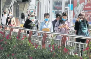  ?? PORNPROM SATRABHAYA ?? People can be seen wearing face masks and using mobile phones at a skytrain station in Bangkok yesterday as telecom operators discussed ways to boost internet connectivi­ty for their customers working from home.