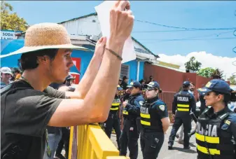  ?? Ezequiel Becerra / AFP / Getty Images ?? A university student confronts police officers Thursday near the Presidenti­al House in San Jose, Costa Rica. Public sector unions went on strike Monday over economic policies.
