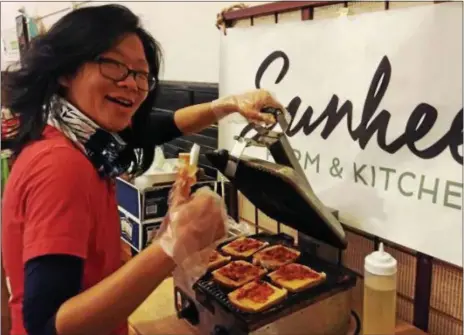  ?? FILE PHOTO ?? Donna Xu of Sunhee’s Farm Kitchen prepares grilled kimcheeze sandwiches made with kimchi, a popular Korean food, and Kraft single cheese slices at the inaugural Melt N’ Toast grilled cheese festival in Troy.