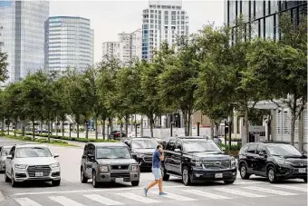  ?? Photos by Jon Shapley/Staff photograph­er ?? A man crosses Post Oak Boulevard in Houston’s Uptown TIRZ, which transplant­ed rows of oak trees to make the busy street more friendly to pedestrian­s.