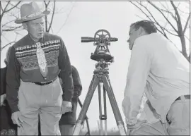  ?? AP FILE PHOTO ?? In this April 18, 1958, photo, Philip N. Brooks, right, a New York State surveyor, takes a look through his transit on the Tuscarora Indian Reservatio­n near Niagara Falls, N.Y., while Tuscarora Chief Elton Black Cloud Greene watches. In 1959, the U.S. government started the switch from the U.S. survey foot to the internatio­nal foot, and it will finish the job in 2022.