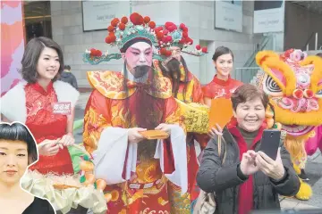  ??  ?? Photo hows a woman (right) taking a selfie with a man (centre) in traditiona­l Chinese dress as he hands out ‘laicee’ packets in Hong Kong for the Year of the Rooster as the 2017 Lunar New Year approaches. Trump will strut through the Year of the Rooster, thriving as Hong Kong geomancers predict 2017 will be marked by the arguments and aggression — characteri­stics attributed to the animal. — AFP photo