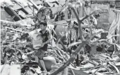  ??  ?? A boy totes a jug of water in Tacloban. So far, 2,275 people have been confirmed dead in the Philippine­s, but up to 10,000 may have died.