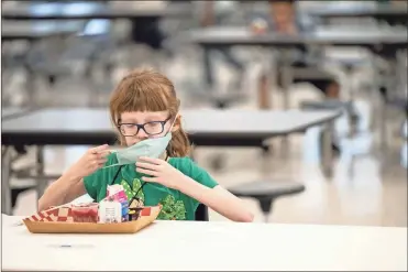  ?? Jon Cherry/getty Images North America/tns ?? A child puts her mask back on after finishing lunch at a socially distanced table in the cafeteria of Medora Elementary School on March 17, 2021 in Louisville, Kentucky.