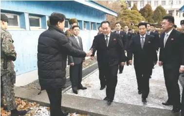  ?? KOREA POOL VIA AP ?? The head of the North Korean delegation, Ri Son Gwon, center, is greeted by a South Korean official as he crosses the border Tuesday to attend their meeting at Panmunjom in the Demilitari­zed Zone in Paju, South Korea.