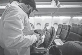  ?? YFFY YOSSIFOR/AP ?? Jamie Shatinsky sprays a disinfecta­nt throughout an American Airlines plane Tuesday at Dallas-Fort Worth Internatio­nal Airport.