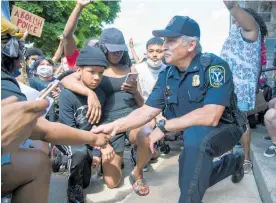  ?? Photo / AP ?? Police Chief Tony DeGiusti shakes hands with a protester while taking a knee with demonstrat­ors in a moment of solidarity during a police brutality protest in downtown Ypsilanti, Michigan.