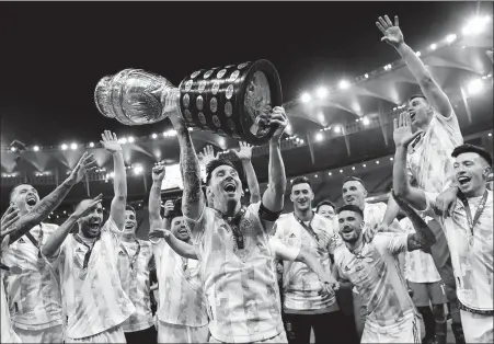  ?? REUTERS ?? Lionel Messi hoists the Copa America trophy and celebrates with teammates after Argentina defeated Brazil 1-0 in Saturday’s final at the Maracana Stadium in Rio de Janeiro, Brazil.
