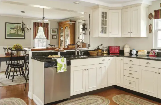  ??  ?? The kitchen is frankly new with white cabinets and dark green granite counters. A wall was removed to open the kitchen to the adjoining dining room, and a new breakfast bar acts as a room divider. The two pendants over the bar were designed by the...