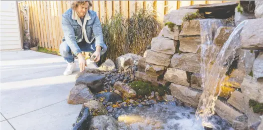  ?? THE HOLMES GROUP ?? To help make the exterior of your home inviting, you can blend ambient, accent, and task lighting. Above, Michael Holmes, on location for Holmes Family Rescue, examines accent lighting for a water feature.