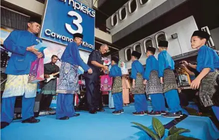  ?? [FOTO ZULFADHLI ZULKIFLI/BH] ?? Noor Rashid (tiga dari kiri) bersama Pengarah Cawangan Khas, Datuk Seri Mohd Fuzi Harun (dua dari kiri) menyerahka­n sumbangan hari raya kepada anak-anak yatim Pusat Jagaan Al-hidayah pada Majlis Jamuan Aidilfitri Cawangan Khas di Bukit Aman, semalam.