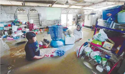  ??  ?? Rosma Zulaiha Zulkefeli, 28, (right) with her brother Adam Izham, 14, removing kitchen items in their home that was inundated during heavy rains in Kampung Nyatuh in Setiu yesterday. – BERNAMAPIX