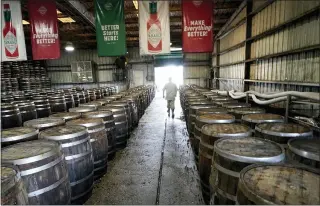  ?? GERALD HERBERT — THE ASSOCIATED PRESS ?? David Botkin, a mash warehouse technician, walks among barrels of Tabasco pepper mash that is being aged, at the McIlhenny Company on Avery Island, La. The company has been brewing Tabasco Sauce since 1868on Avery Island — the tip of a miles-deep column of salt — and now fills up to 700,000 bottles a day, selling them in 195countri­es and territorie­s.