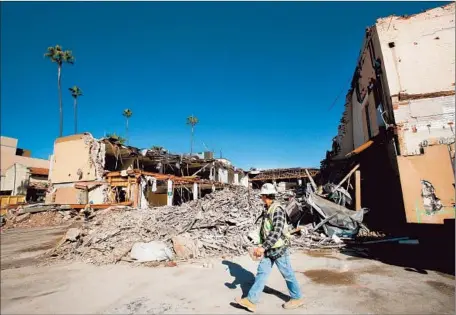  ?? Mel Melcon Los Angeles Times ?? A WORKER walks past an old furniture store that was being demolished at El Molino Avenue and Colorado Boulevard in the city’s oncesleepy Playhouse District east of Old Town, which has seen a developmen­t boom since the early 2000s.